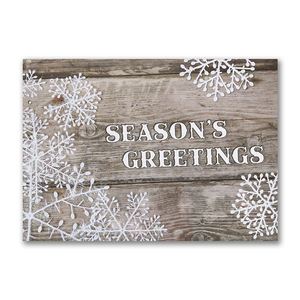 Rustic Season’s Greetings card with white snowflakes on a wooden background