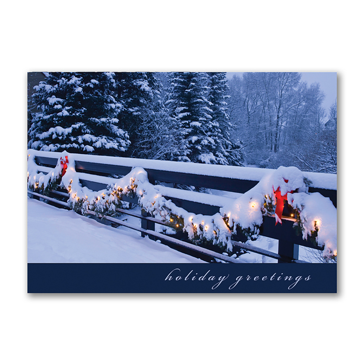 Holiday greetings card featuring a snow-covered fence decorated with garland lights and red bows