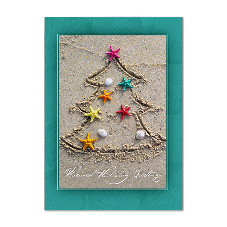 Warm holiday greetings card featuring a Christmas tree drawn in sand with colorful starfish and seashells