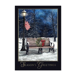 Season’s Greetings card featuring a snow-covered park bench with a holiday wreath and American flag under a winter night sky