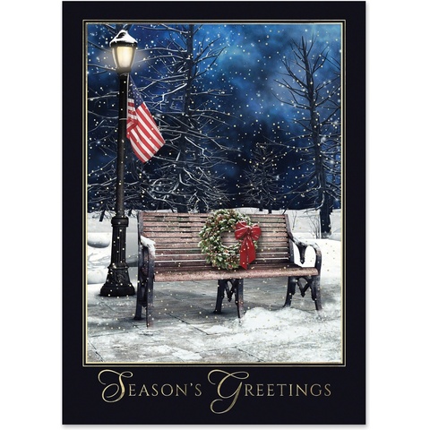 Season’s Greetings card featuring a snow-covered park bench with a holiday wreath and American flag under a winter night sky