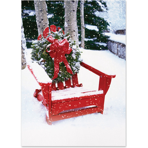 Festive winter holiday card featuring a red Adirondack chair adorned with a Christmas wreath and red bow in a snowy outdoor setting