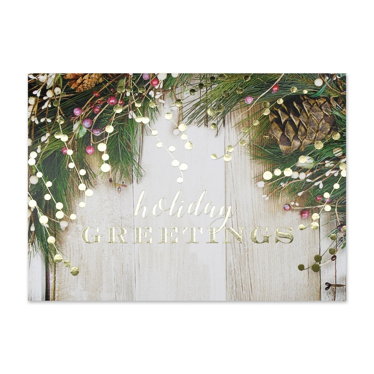 Rustic holiday greeting card featuring pine branches, pinecones, berries, and warm string lights on a weathered wood background