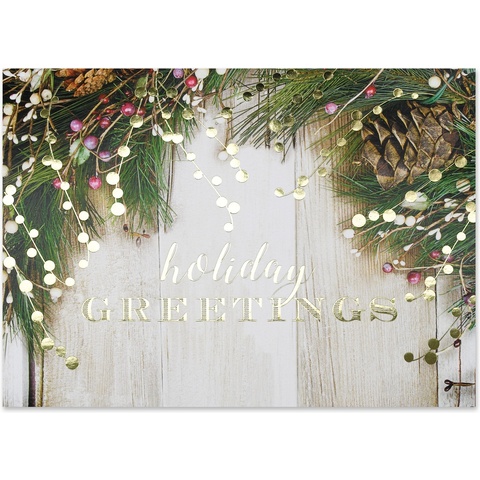 Rustic holiday greeting card featuring pine branches, pinecones, berries, and warm string lights on a weathered wood background